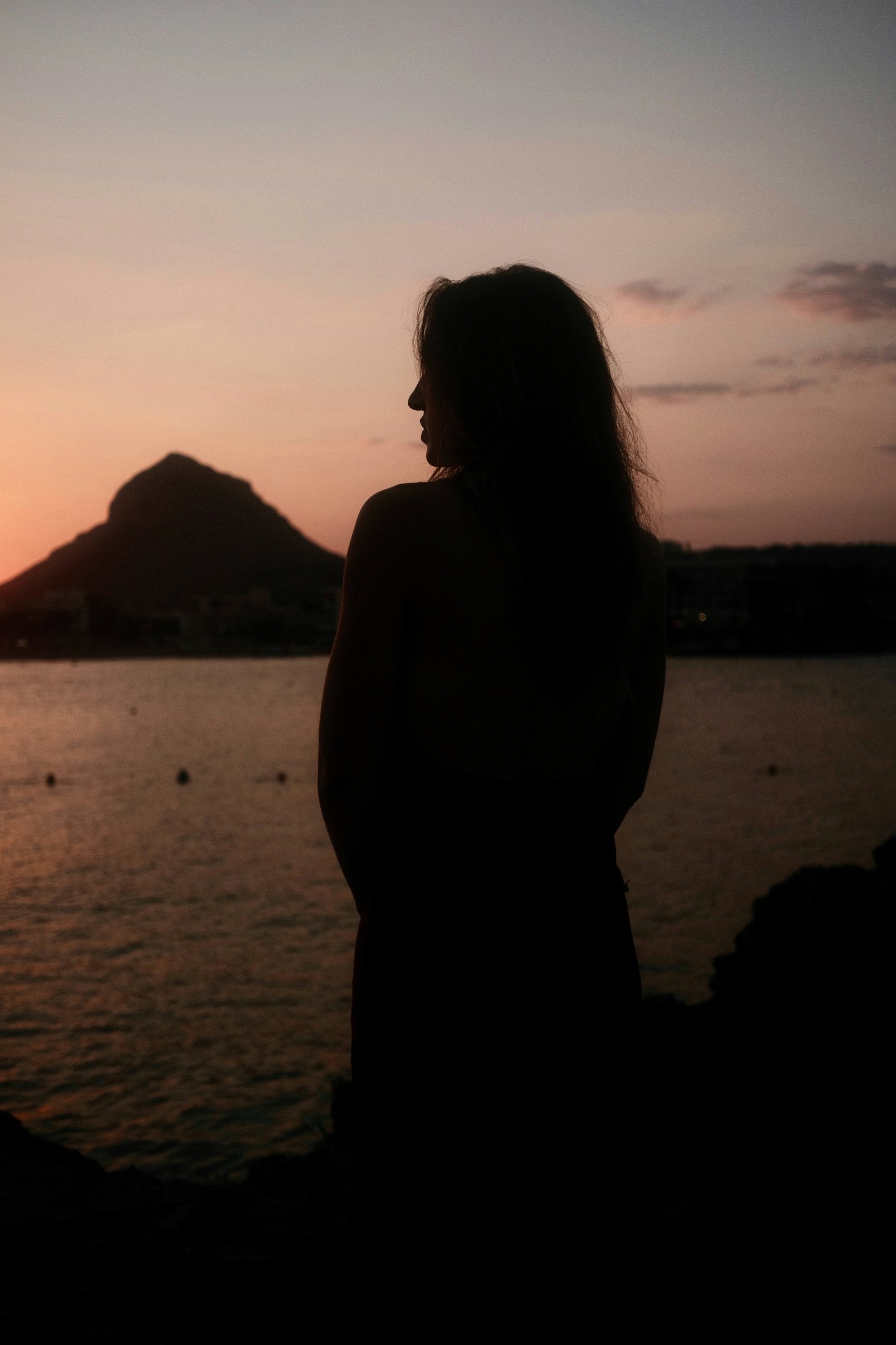 Silhouet van een vrouw bij zonsondergang aan zee